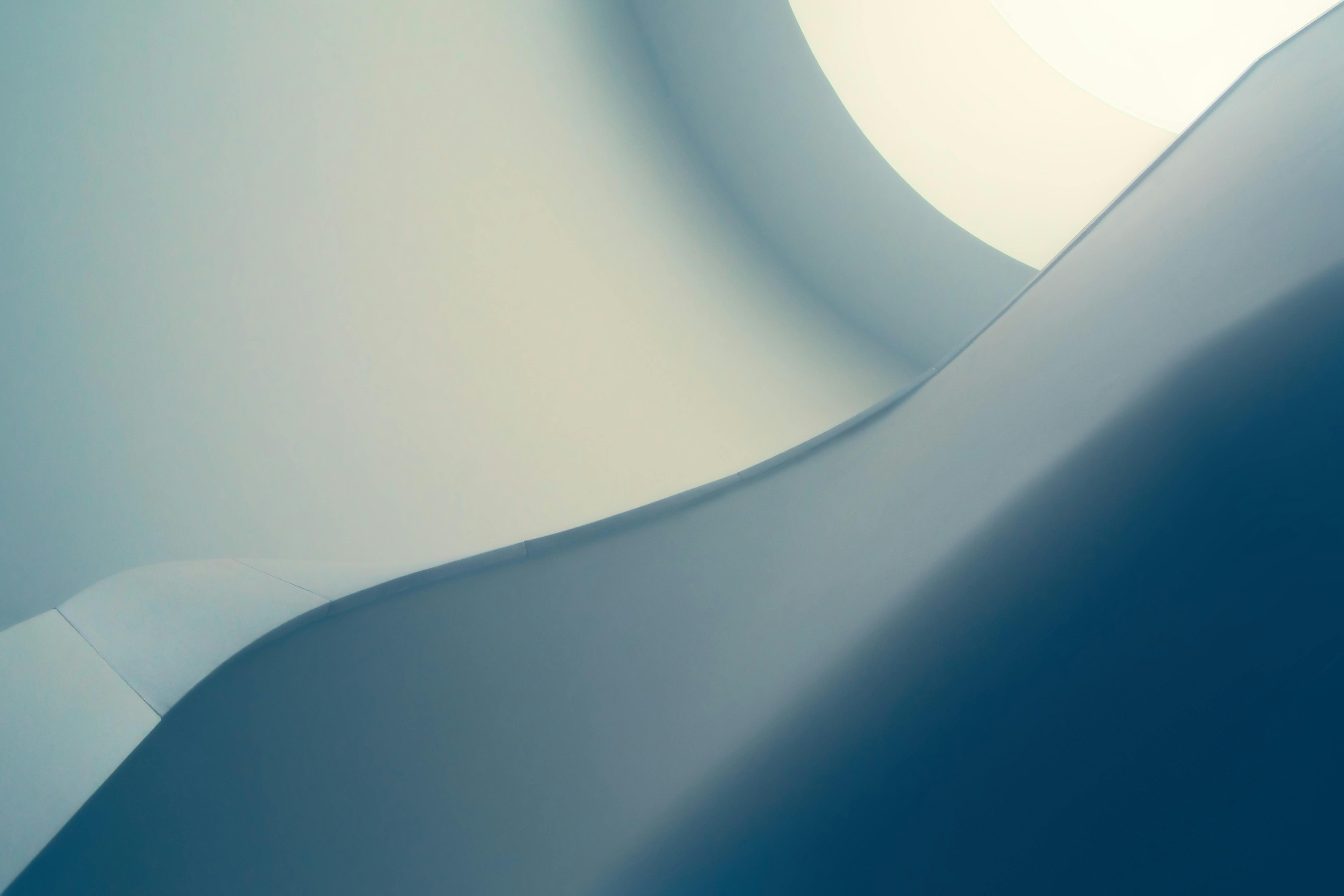 Abstract image featuring smooth, curved surfaces in soft blue and white tones—reminiscent of a dentist’s clean, calming environment—with gentle gradients and a bright circular area in the upper right corner.