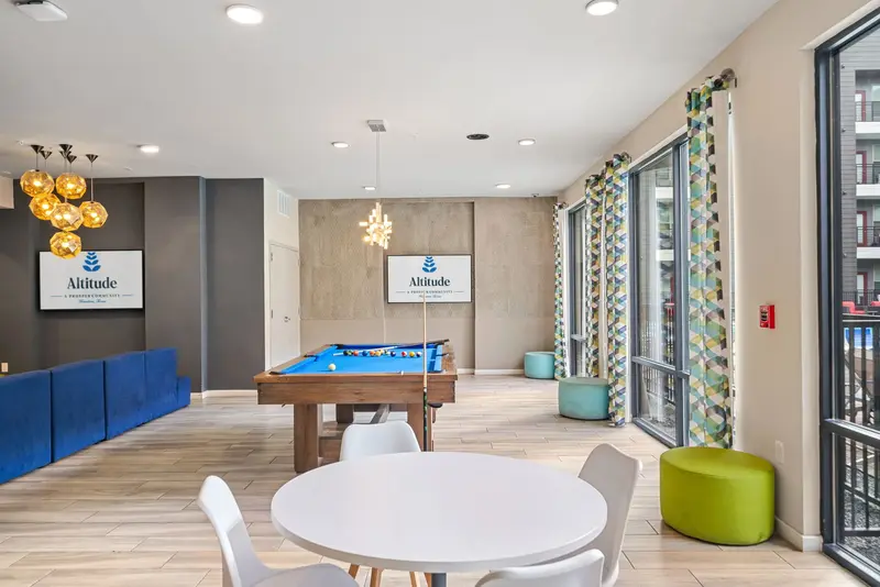 Vibrant resident lounge with a billiards table, comfortable seating, and large windows, perfect for socializing at Altitude in Houston, TX.