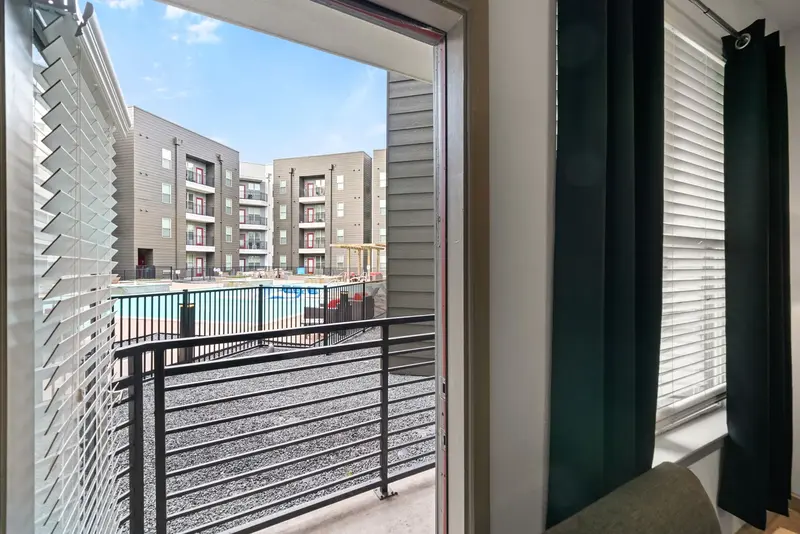 View of the community swimming pool and courtyard from a private balcony, offering outdoor living at Altitude apartments in Houston, TX.