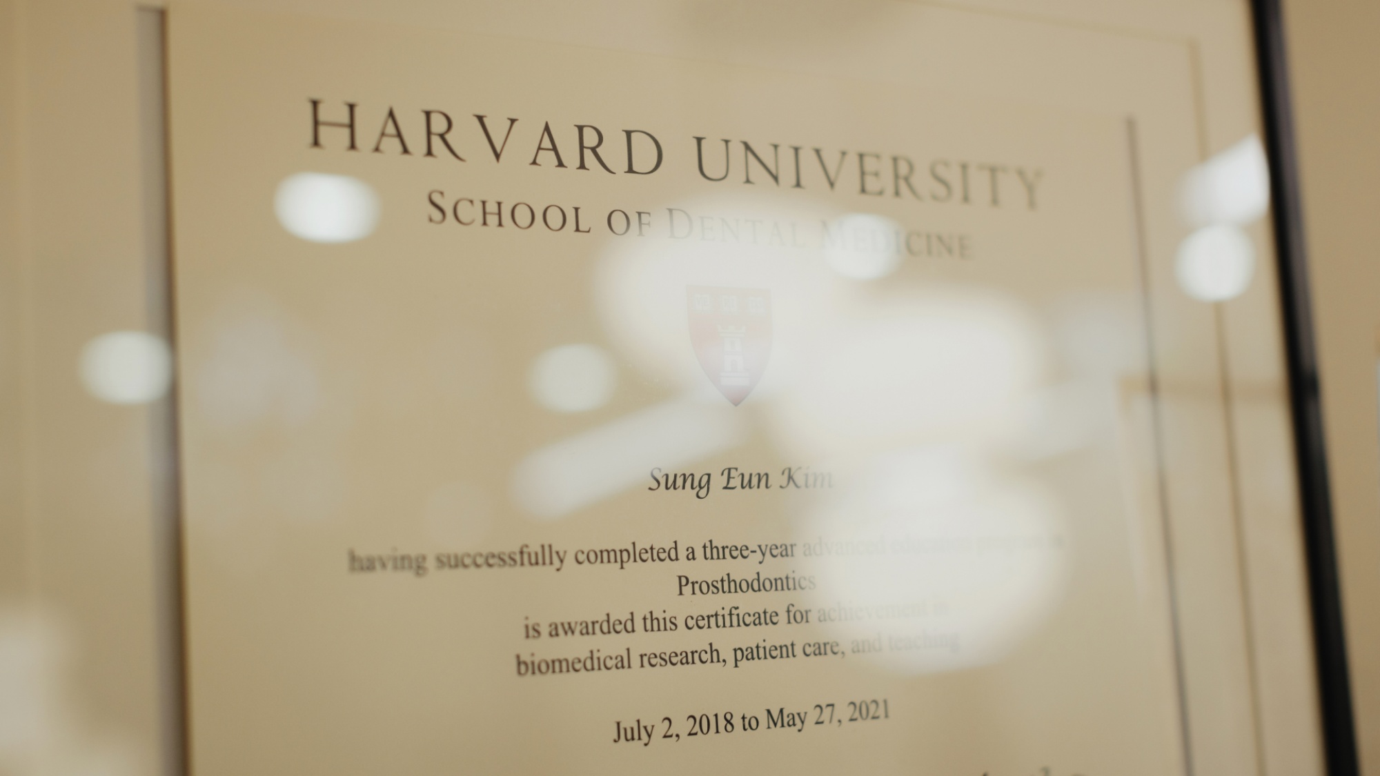A framed certificate from Harvard University School of Dental Medicine awarded to dentist Sung Eun Kim for completing a three-year residency in Prosthodontics at Montvale Prosthodontics, dated July 2, 2018 to May 27, 2021.