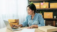 Business owner organizes inventory among shipping boxes
