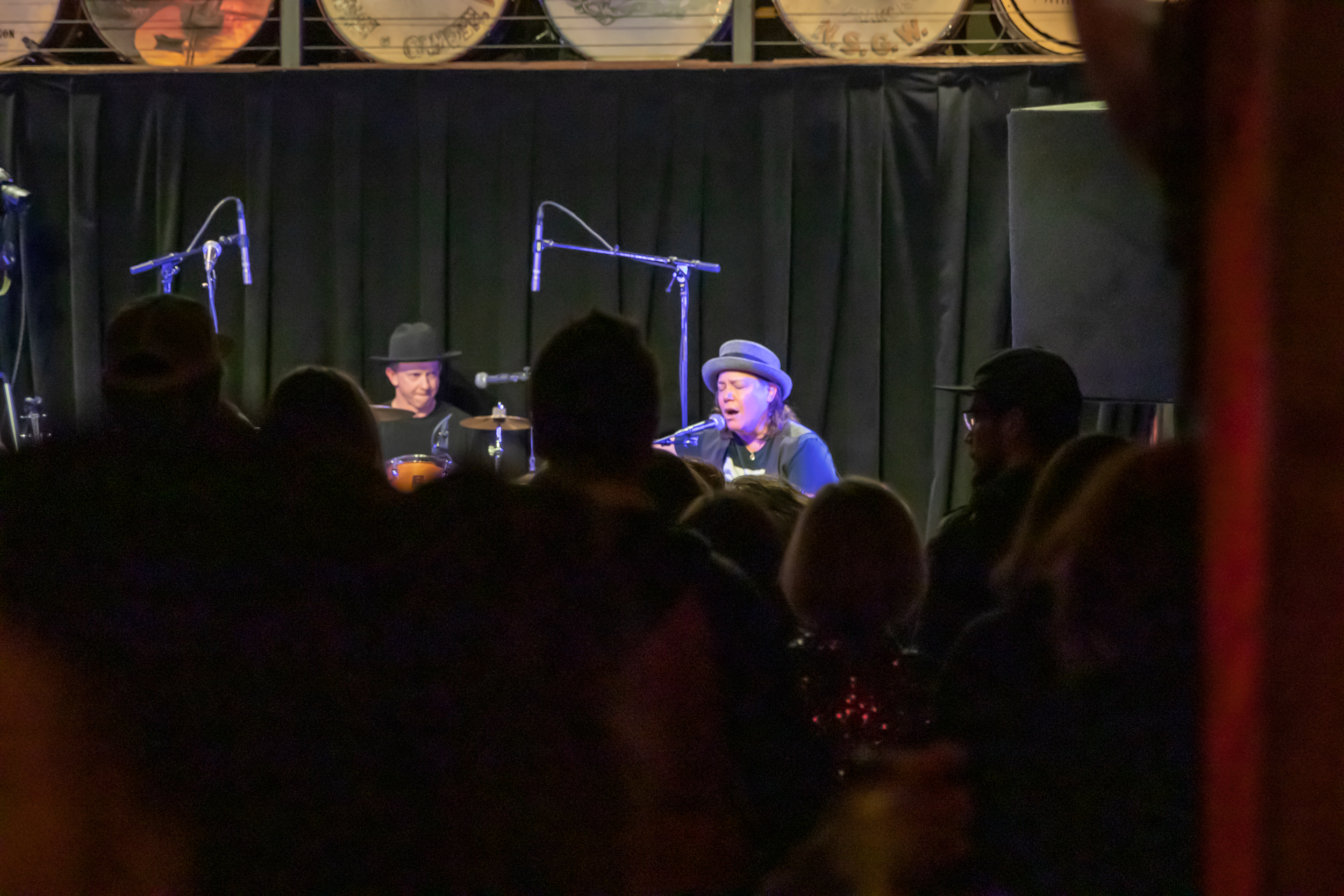 POV shot from the back of the venue and through the crowd listening to Annie Vergnetti on stage in the foreground at Mississippi Studios in 2023.