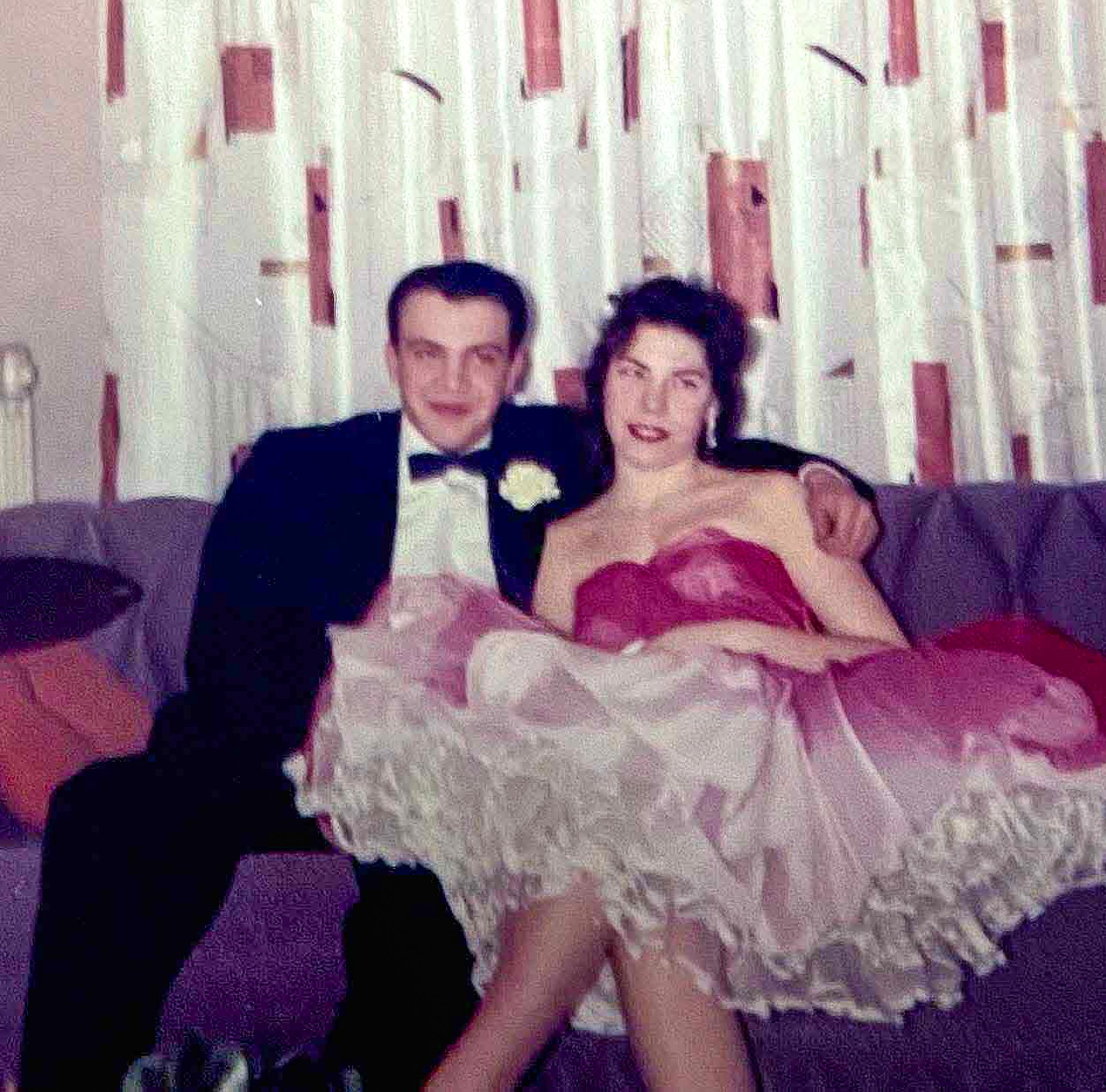 Annie's young parents, looking sharp in formal clothes, posing at a school dance. 