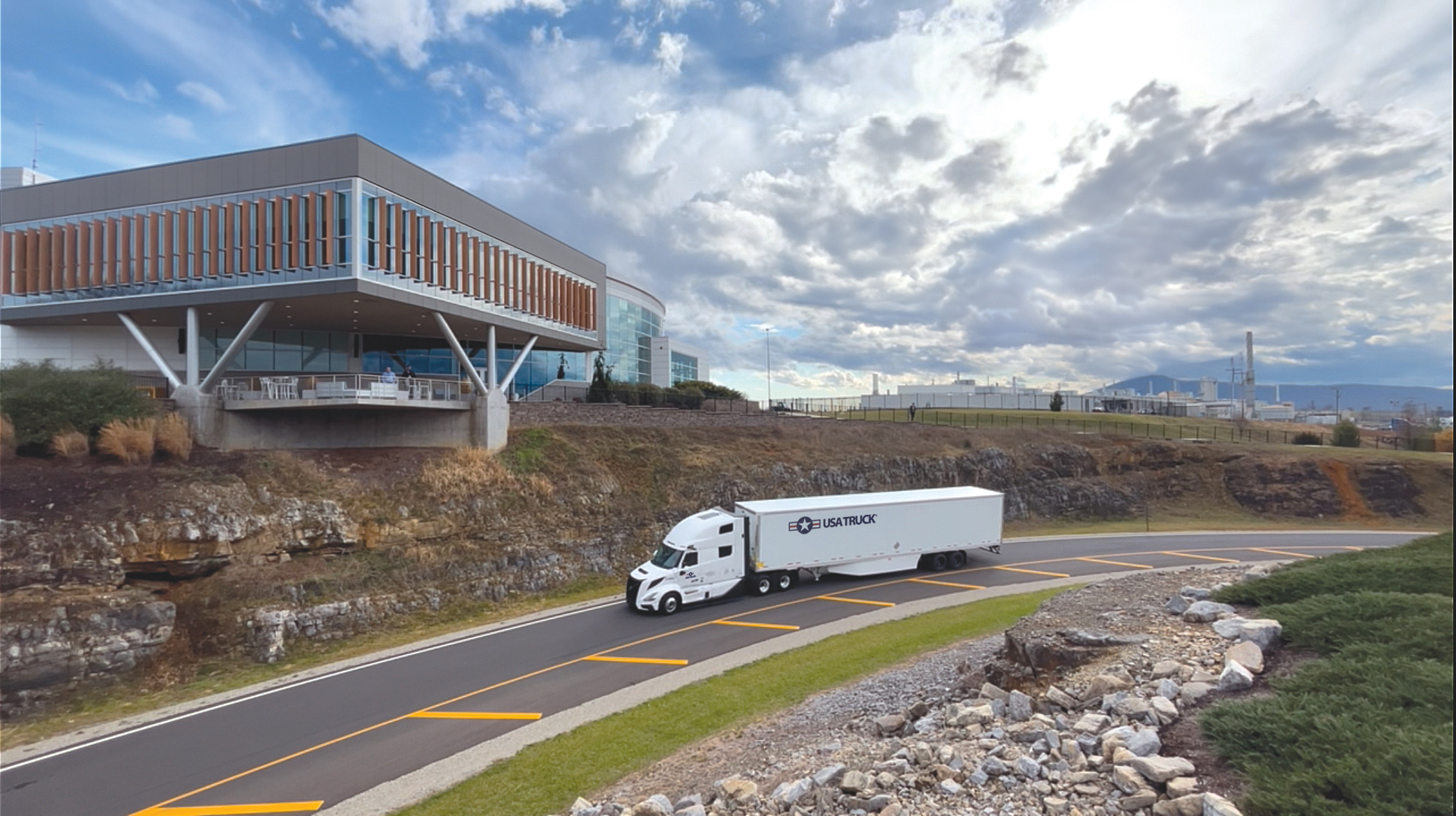 semi truck driving down the road infront of impressive building