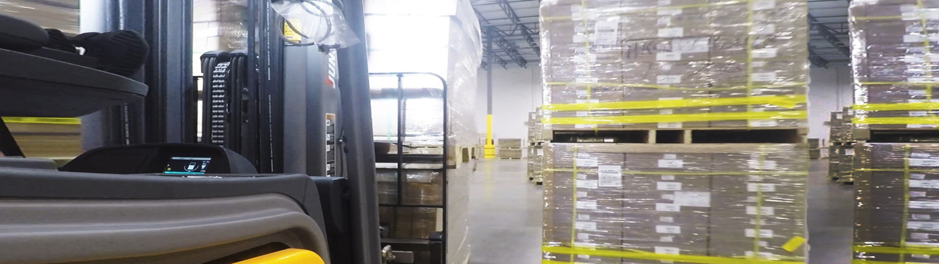 forklift driving past stacked pallets