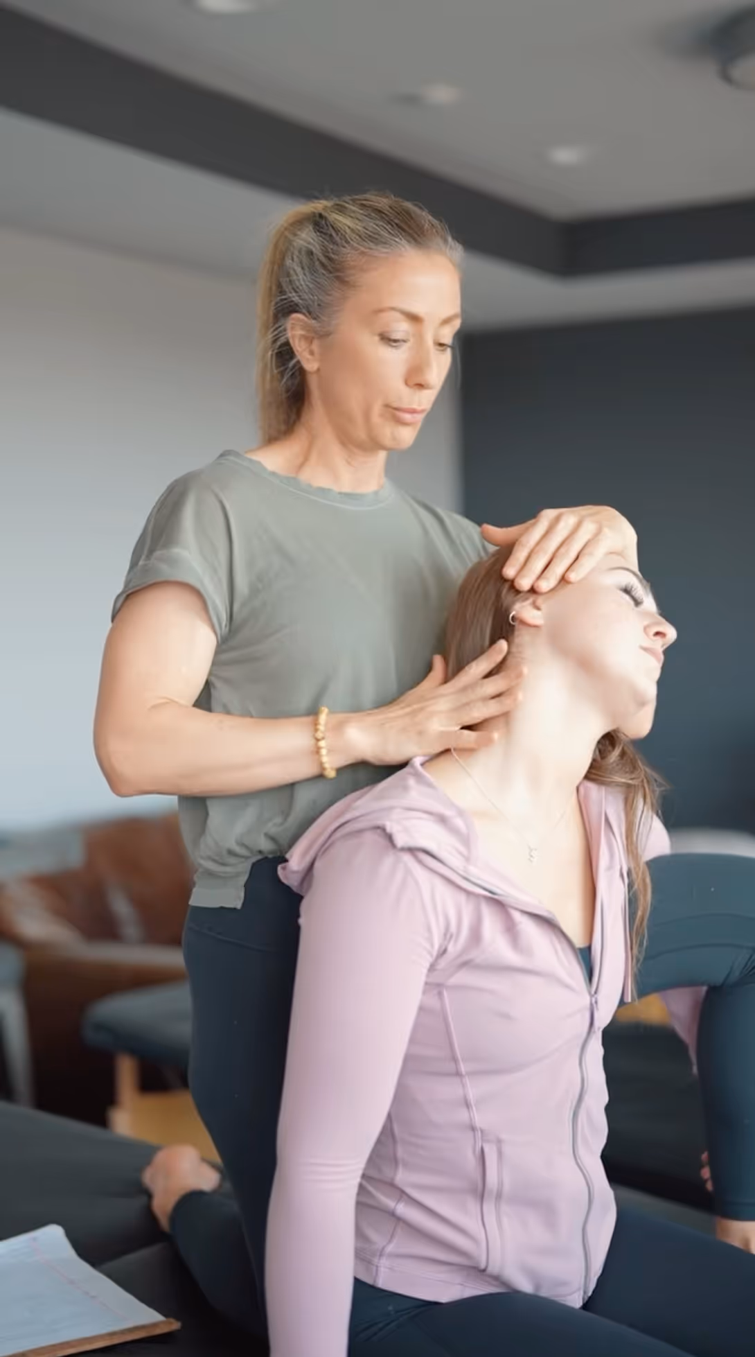 Massage therapist performs head and neck treatment on client