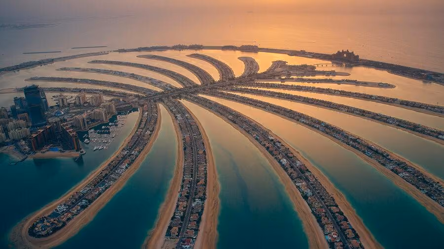 Ein atemberaubender Panoramablick zeigt die Skyline von Dubai mit modernen Hochhäusern am Wasser während des Sonnenuntergangs. Diese beeindruckende Szenerie vermittelt das Gefühl von Luxus und Lebensqualität in den Vereinigten Arabischen Emiraten und könnte als perfekte Kulisse für den Kauf einer Wohnung in Dubai dienen.