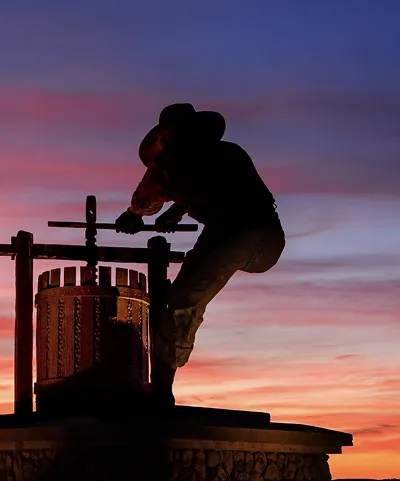 Silhouette of a winemaker using a traditional wine press at sunset in Napa Valley