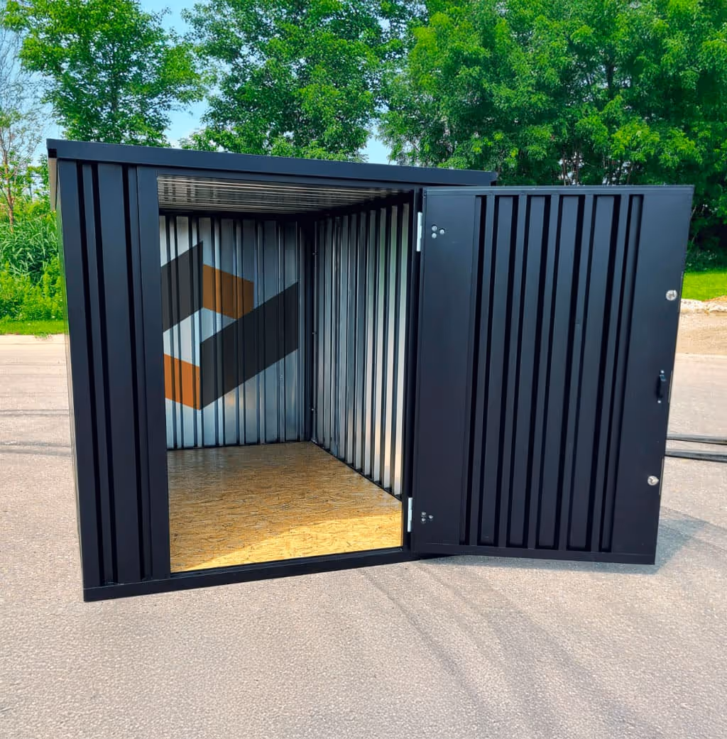 Conteneur de rangement noir métallique ouvert avec sol en bois, extérieur vert