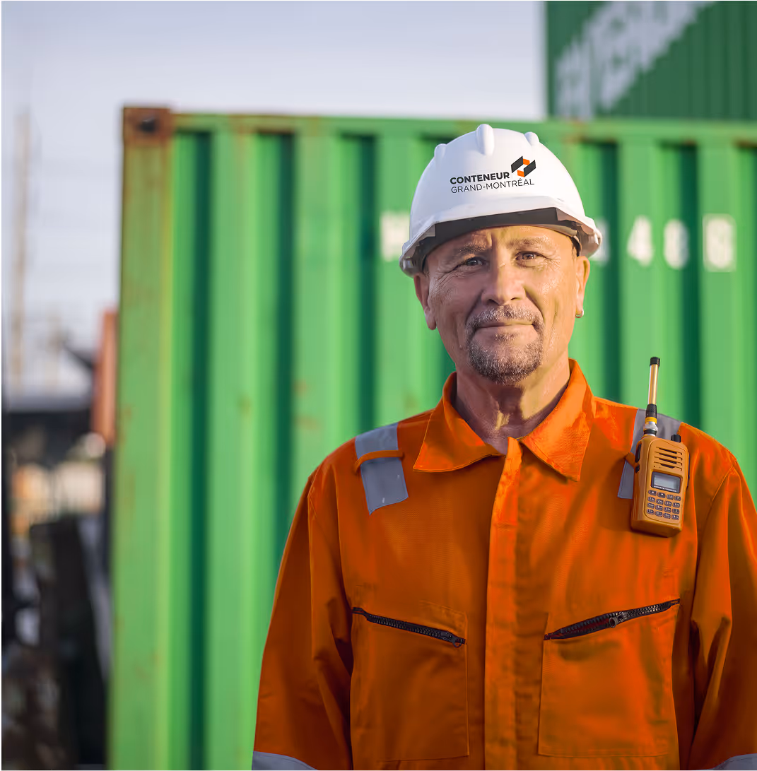 Travailleur portuaire souriant dans un uniforme orange devant des conteneurs verts