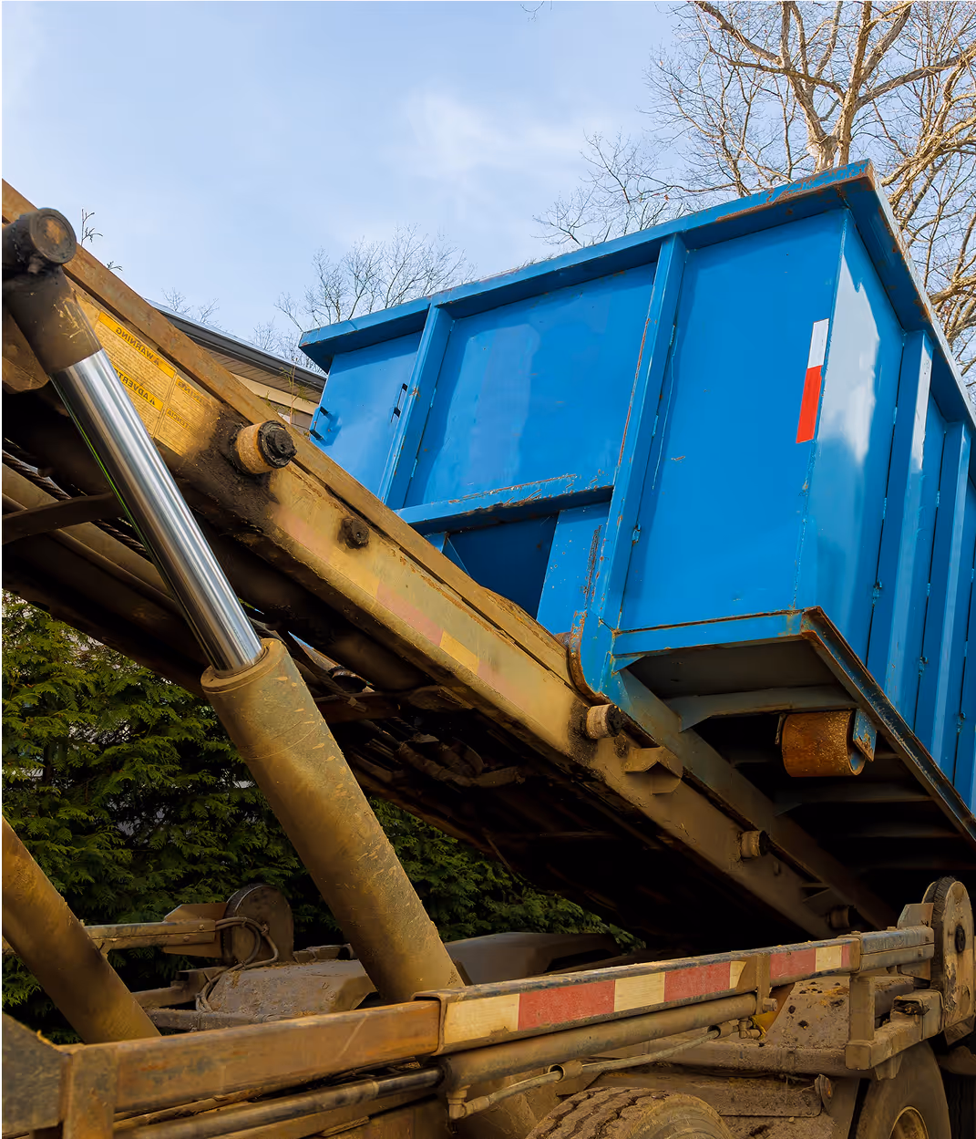 Conteneur bleu de déchets soulevé par un camion hydraulique industriel