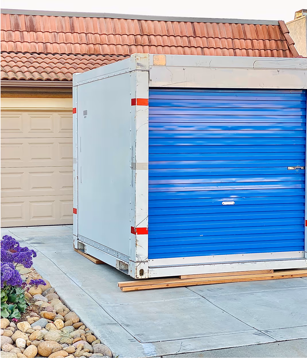 Conteneur de stockage blanc et bleu avec porte roulante près d'un garage