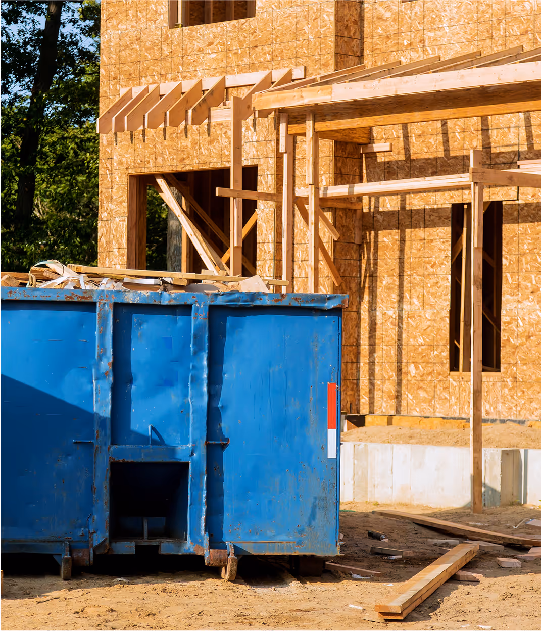 Chantier de construction avec benne bleue et ossature en bois