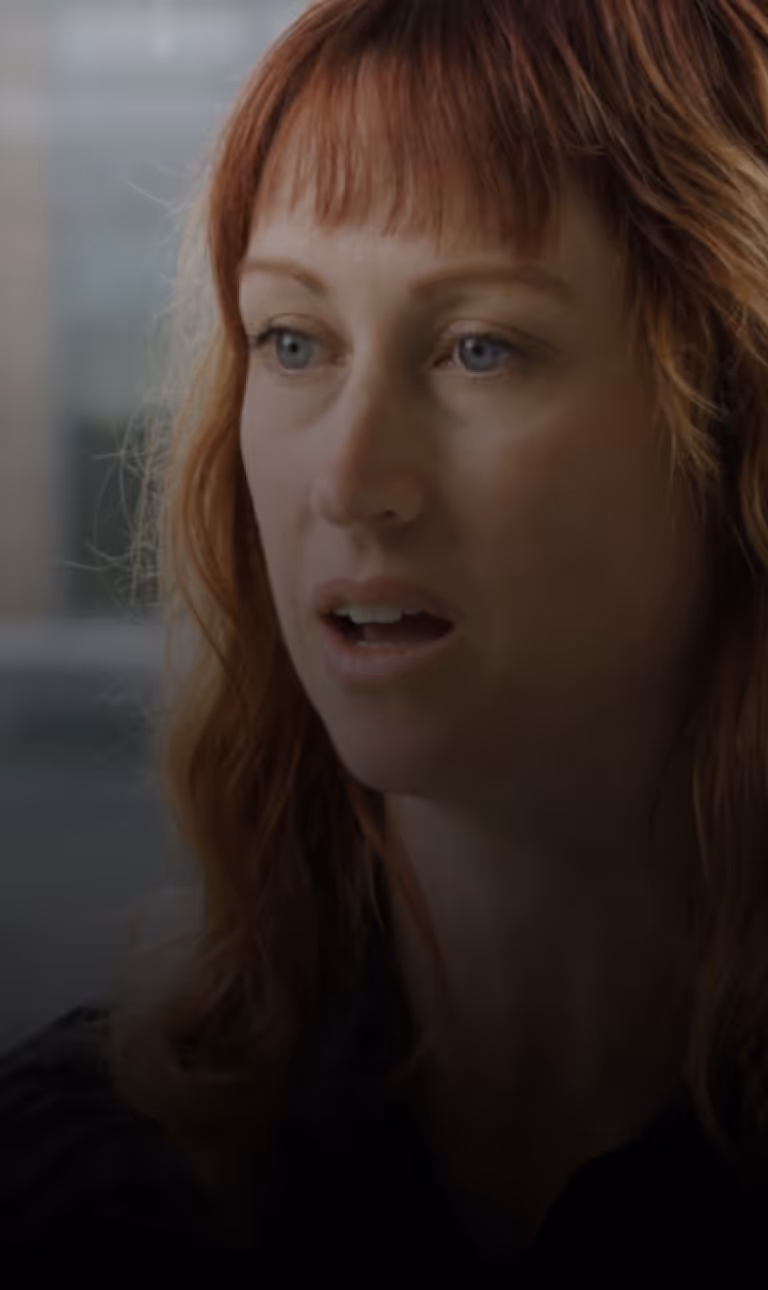 Close-up of a woman with red hair and blue eyes speaking or reacting about CUBEX for universities and teaching hospitals