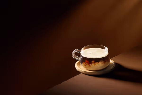 Beverage photography of a coffee set against a warm, dark chocolate background with dramatic lighting.