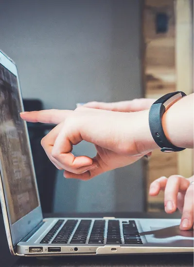 Two people touching hands over a laptop computer.