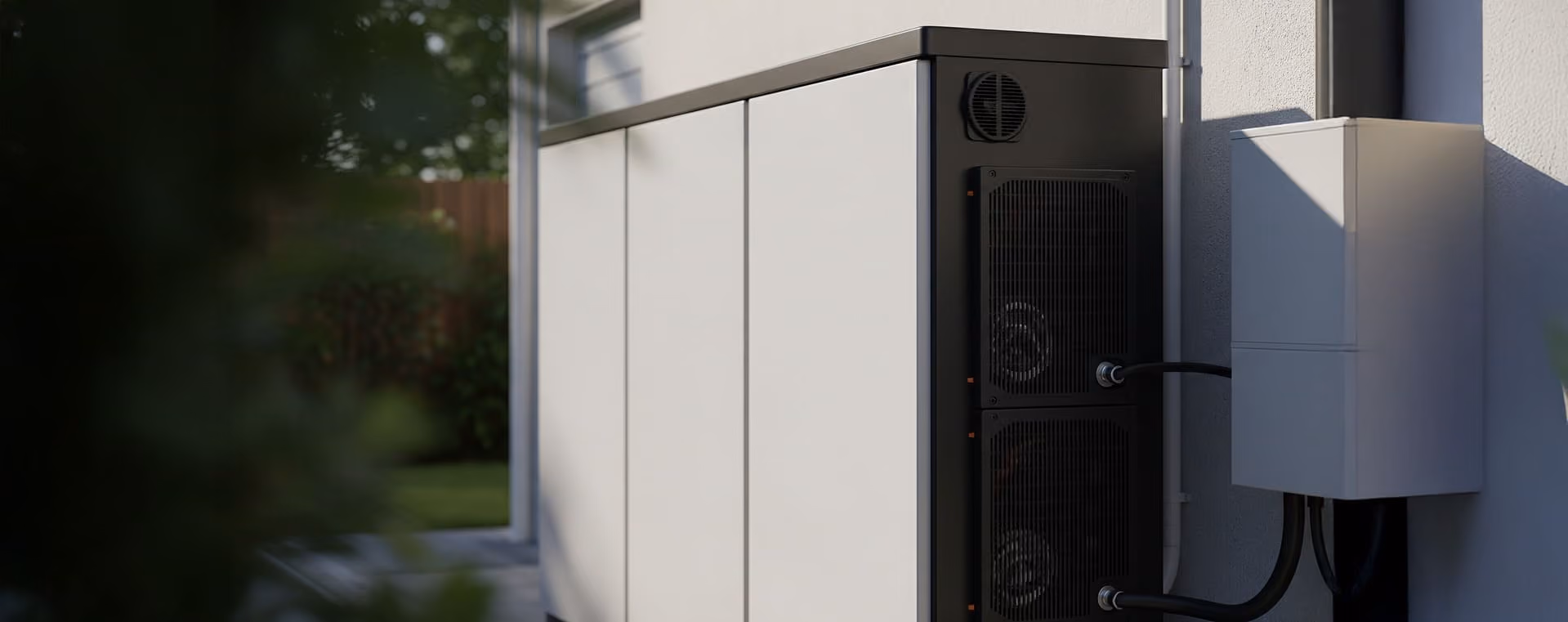 Unité de batterie de stockage d’énergie blanche installée à l’extérieur d’une maison, avec câblage connecté.