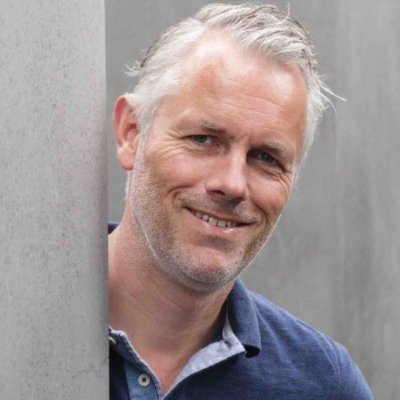 Frank Grevers, witte man van middelbare leeftijd, met grijs haar en lichte baard en blauwe polo