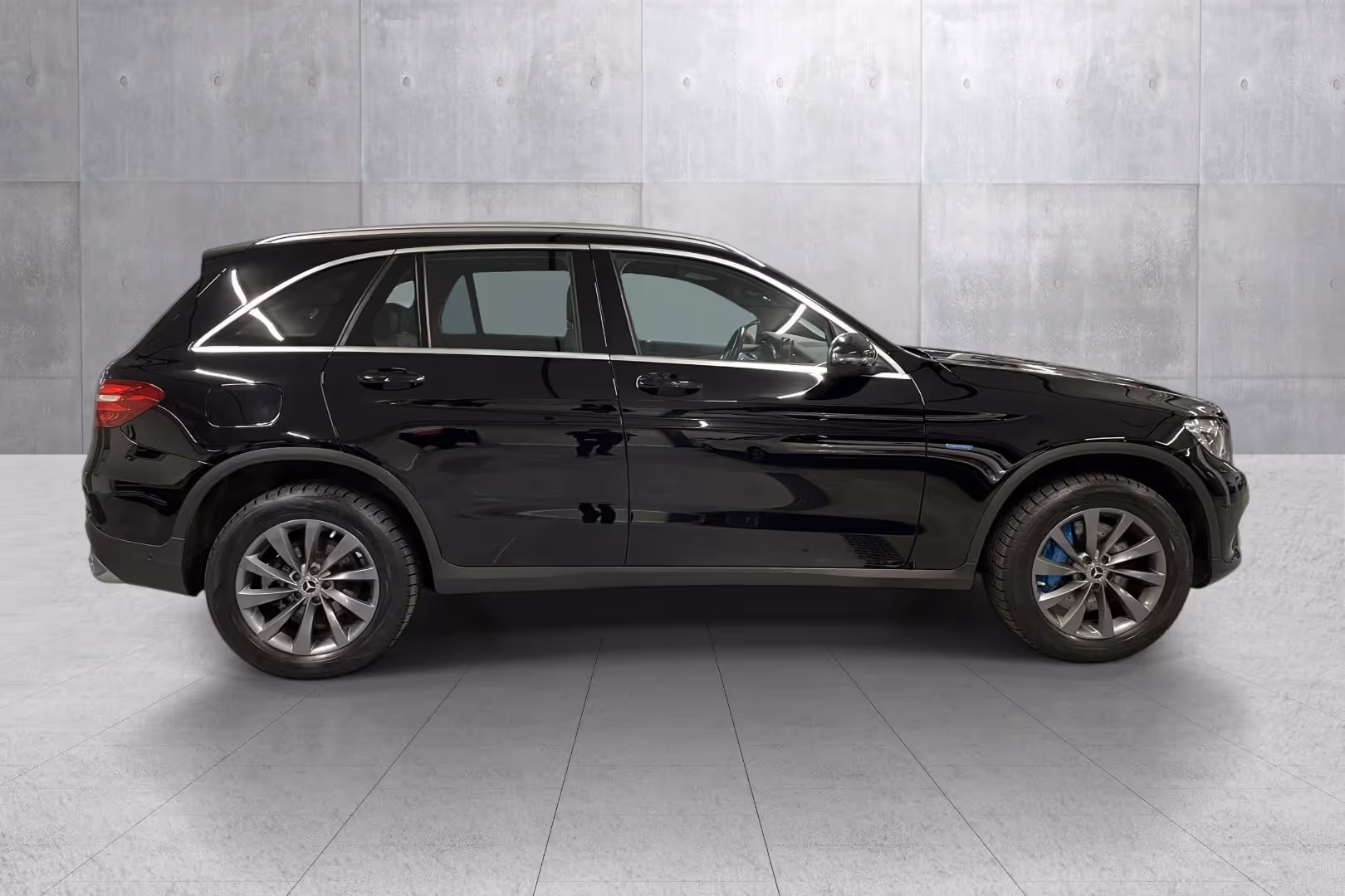 Side view of a black Mercedes-Benz SUV parked indoors against a concrete wall.