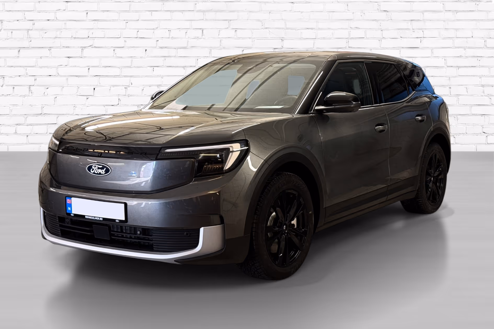 Gray Ford Explorer SUV parked indoors in front of a white brick wall.