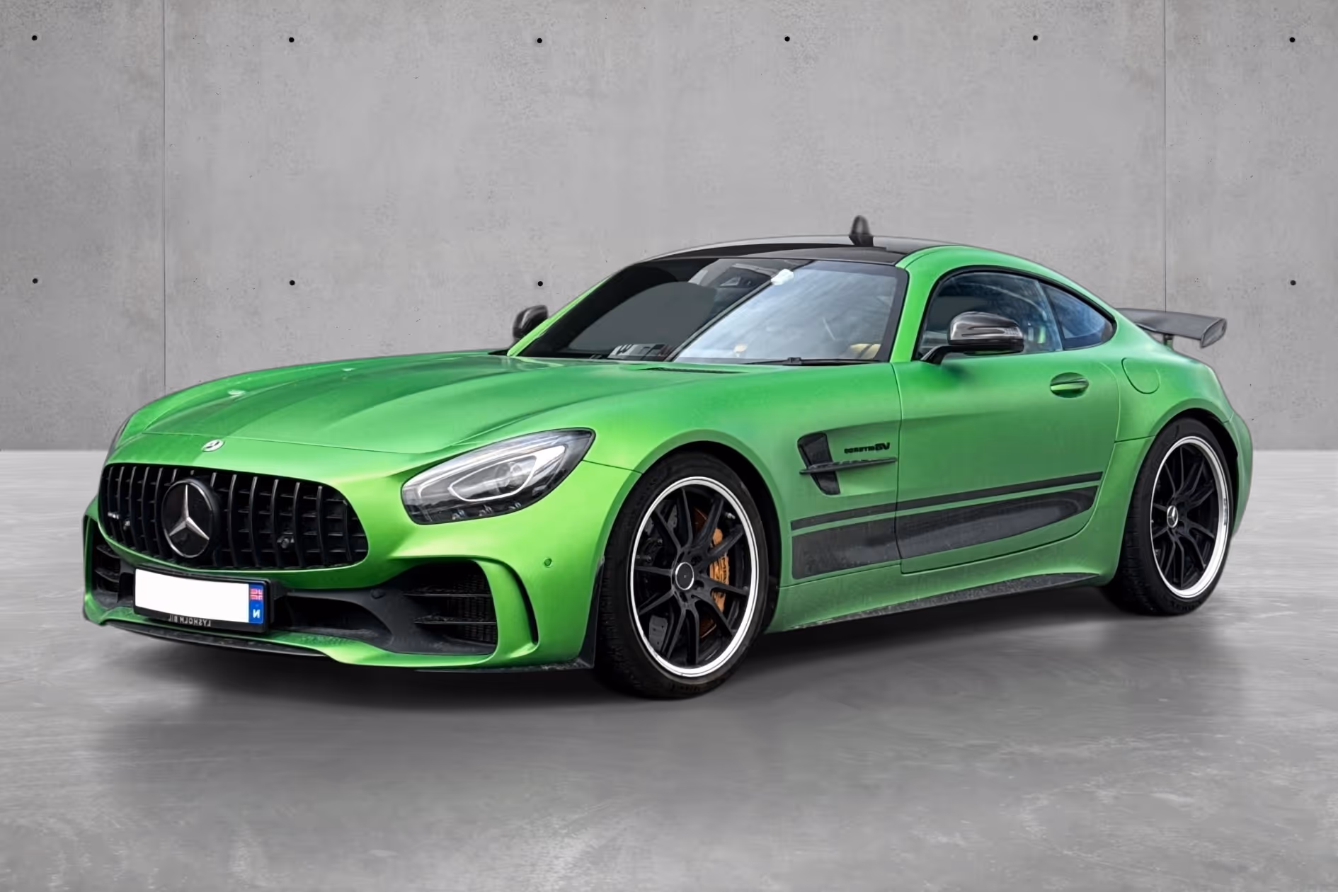 Bright green Mercedes AMG GT sports car parked indoors with black rims and rear spoiler.