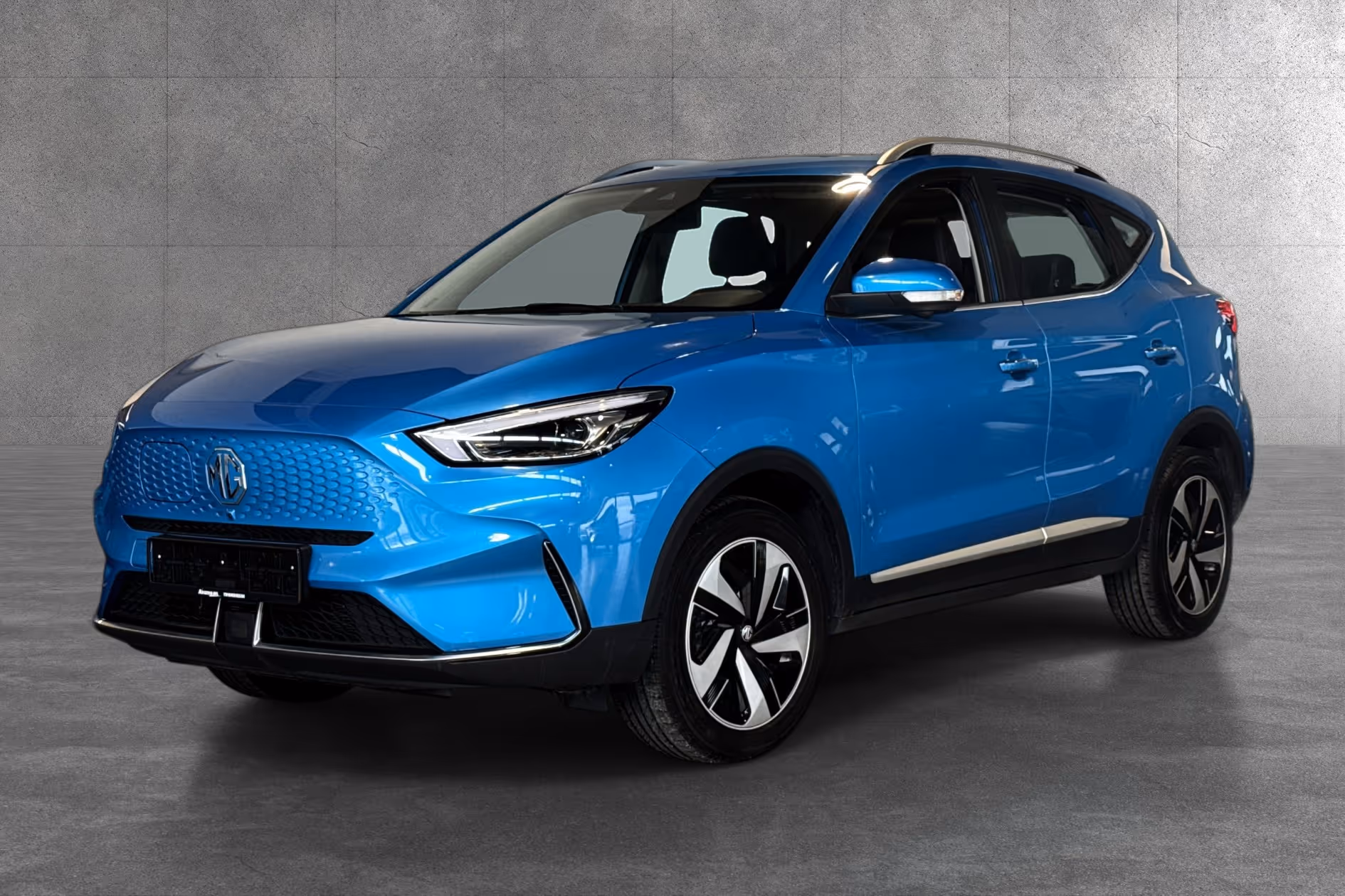 Blue MG compact electric SUV parked indoors with alloy wheels and modern headlights.