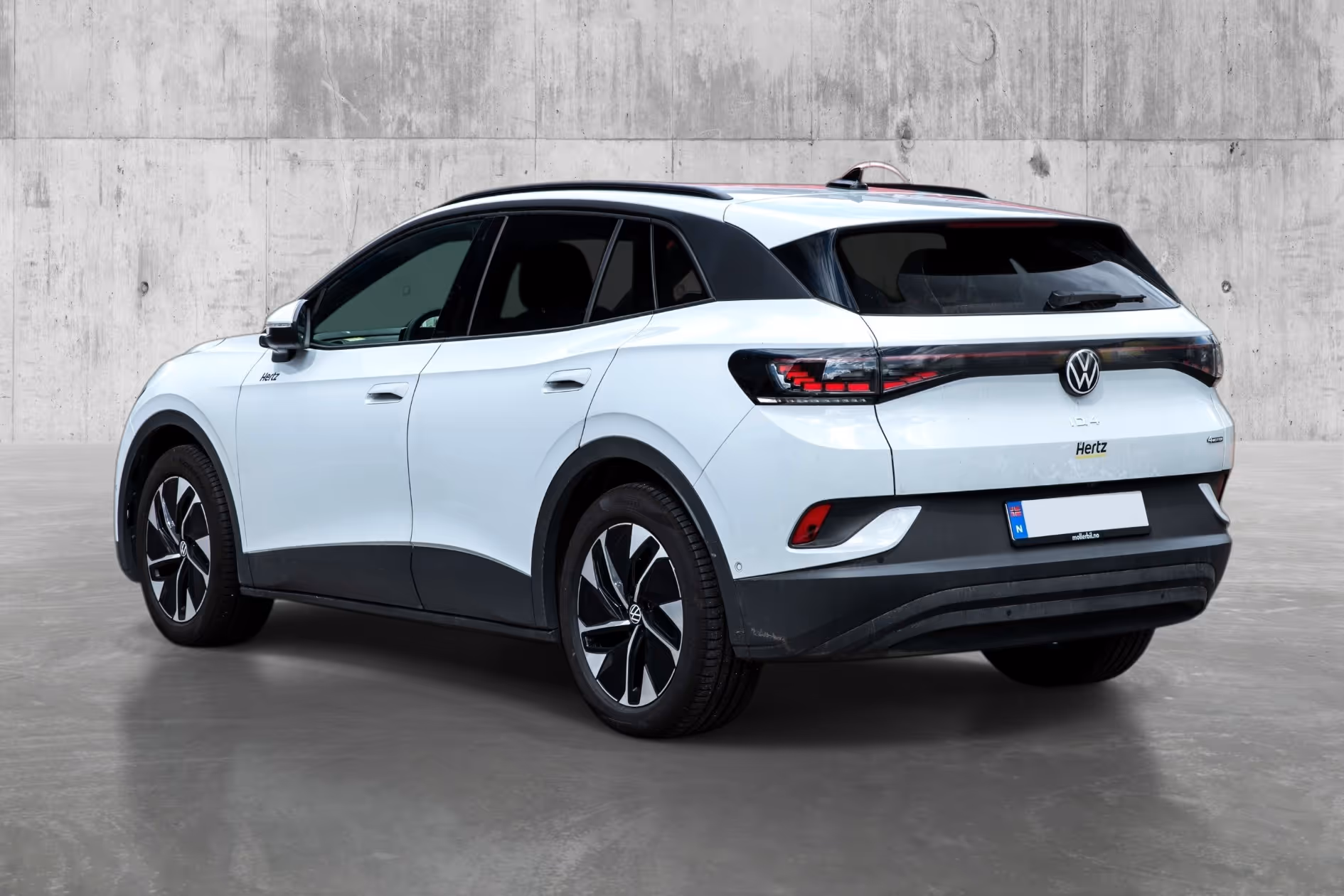 White Volkswagen ID.4 electric SUV parked indoors against a concrete wall.