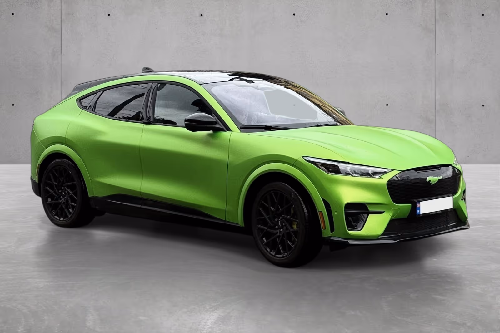 Bright green Ford Mustang Mach-E electric SUV parked indoors on a gray concrete floor.