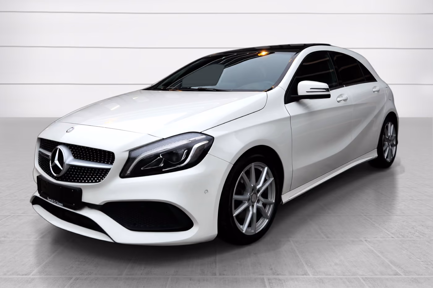 White Mercedes-Benz hatchback parked indoors on a tiled floor.