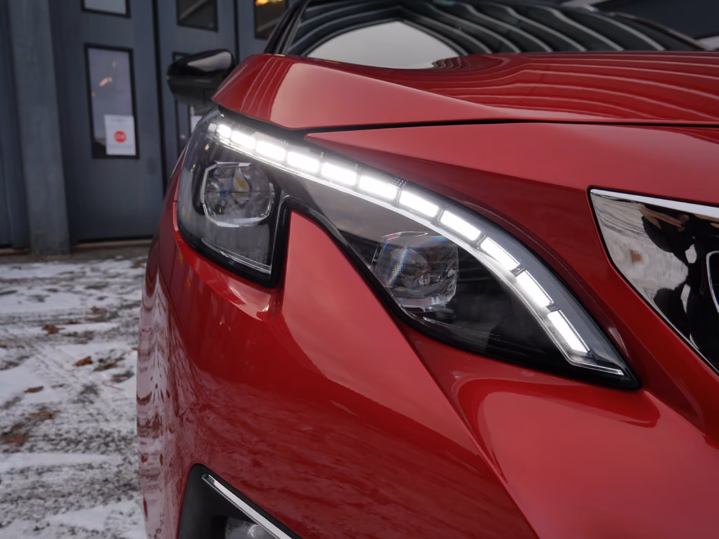 Close-up of a red car's modern headlight with LED daytime running lights illuminated.