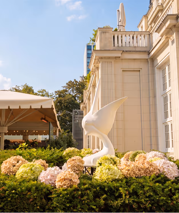 Außenansicht des Pellicano Restaurants mit Blick auf das Gebäude, die Terrasse und die Pellikan Steinfigur.