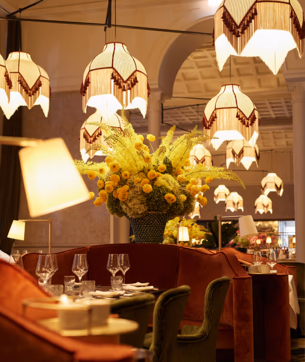 Elegantes Interior im Pellicano Restaurant Hamburg mit üppiger Blumendekoration, stimmungsvoller Beleuchtung und stilvoll eingedeckten Tischen.