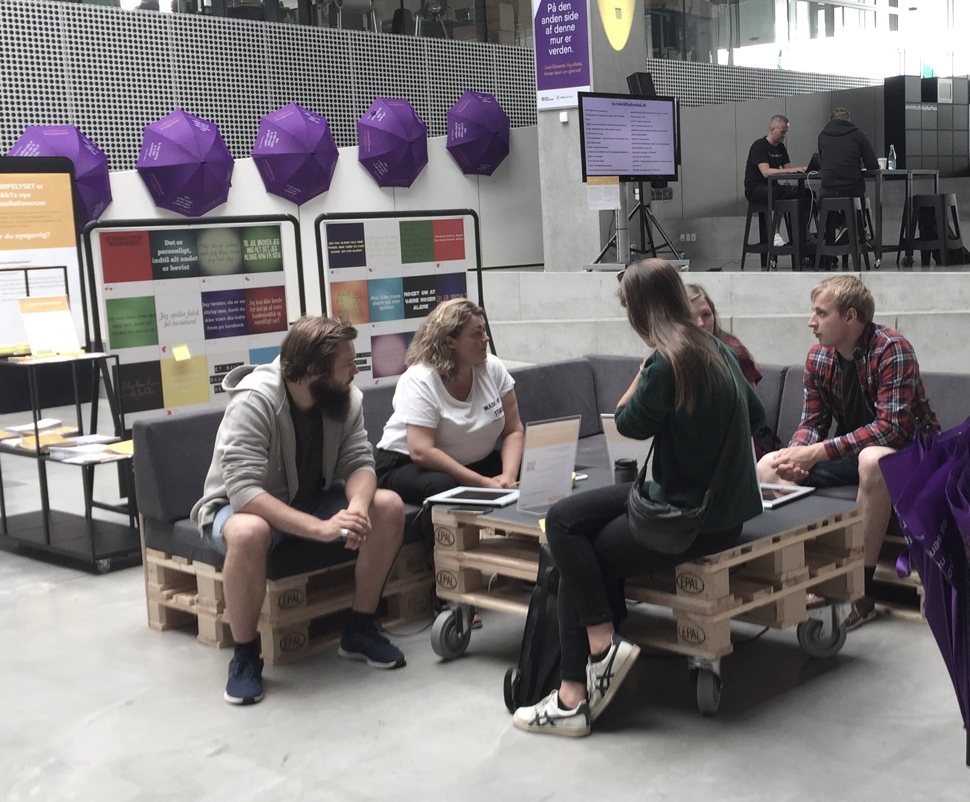 Gruppe mennesker i loungemøbler, der fører en samtale.