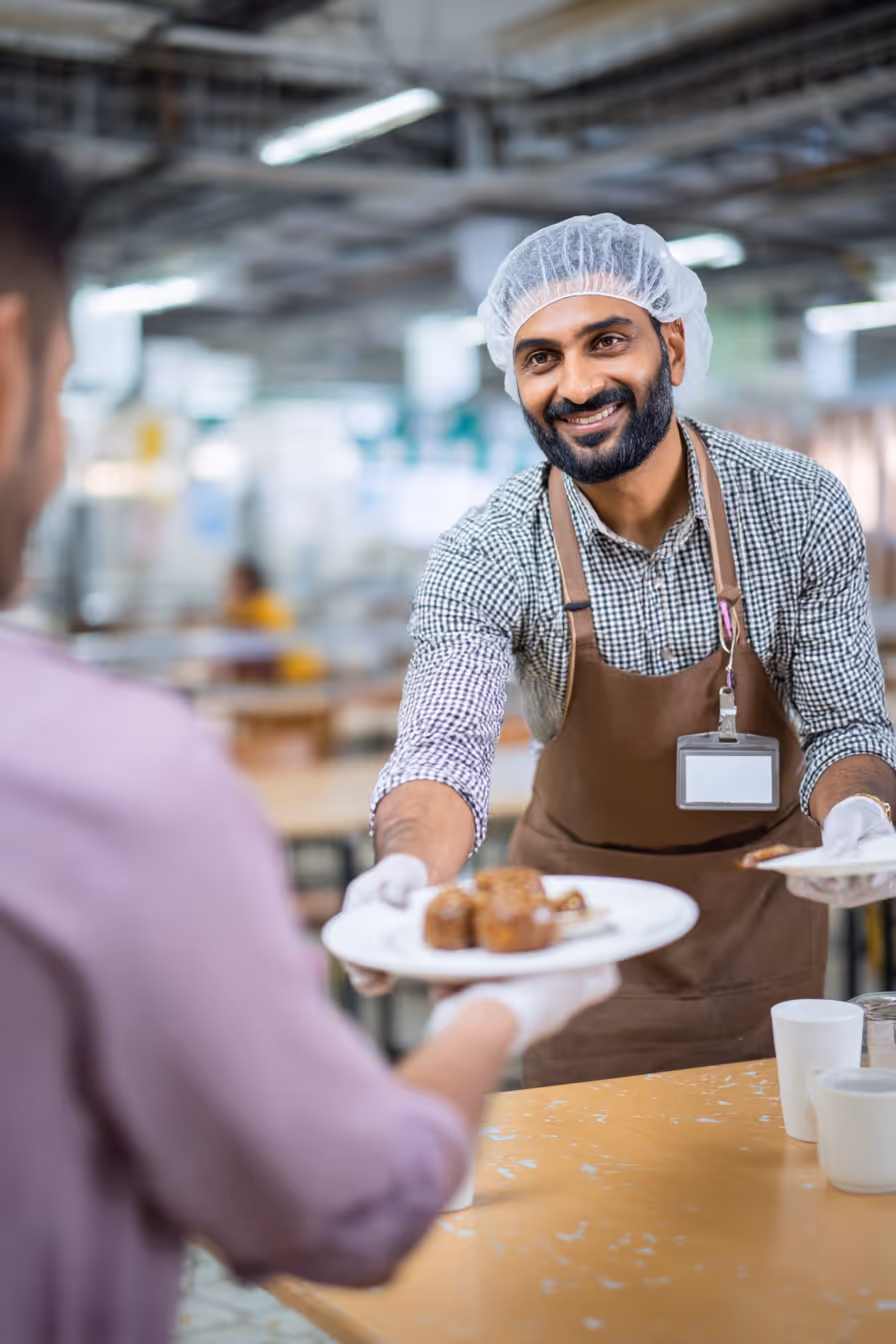 Dedicated food service staff serving corporate catering meals in a clean environment.