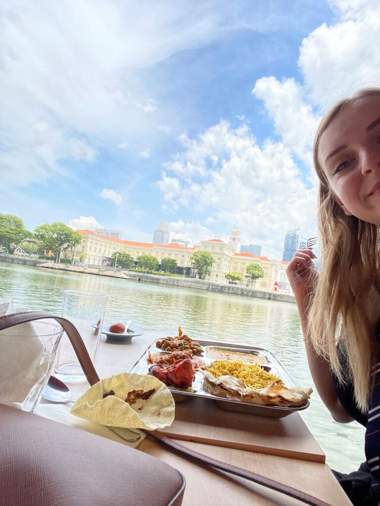 Laura eating food by the water in Singapore.