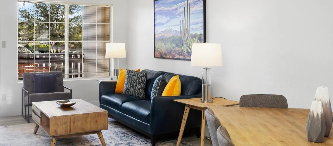 A modern living-dining area with natural light, wooden furniture, and vibrant decor accents.