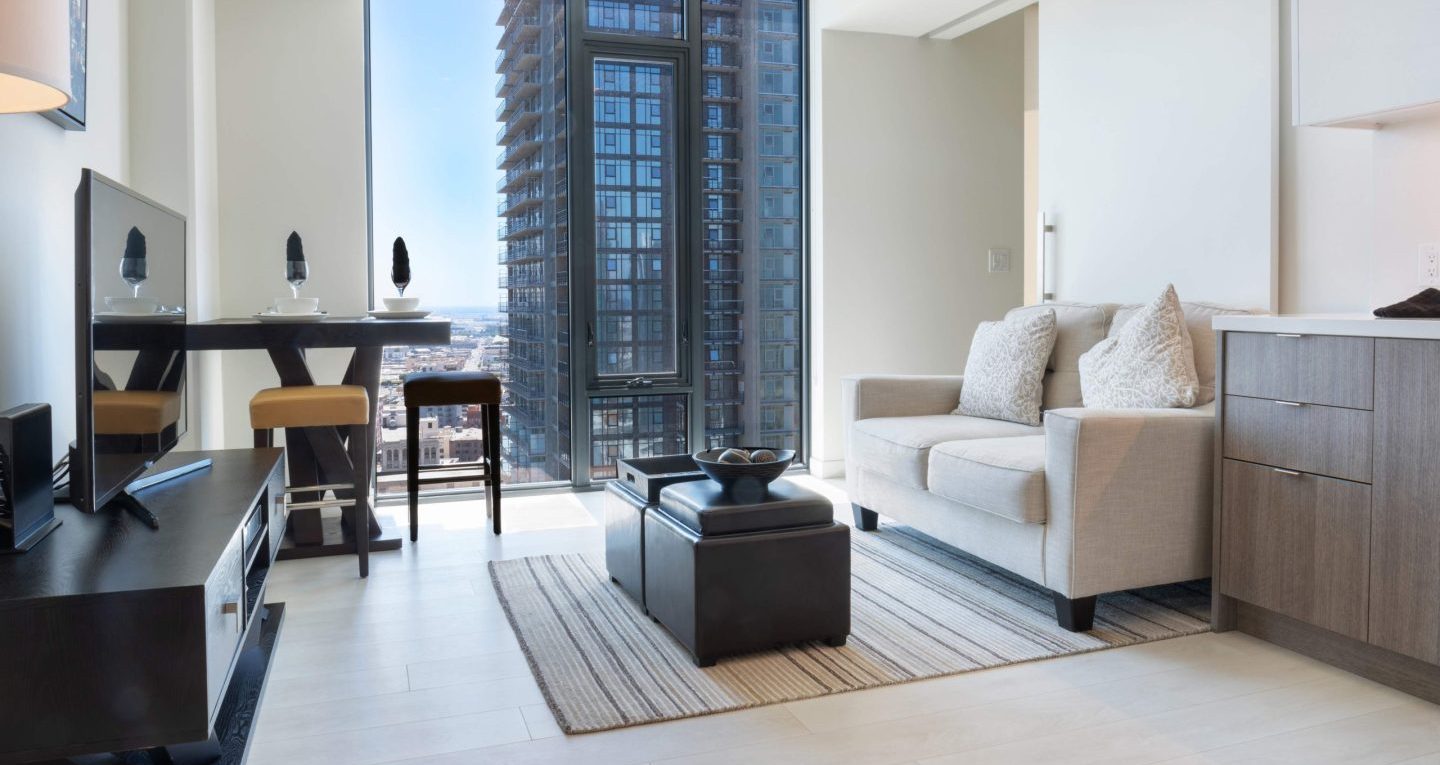 Modern apartment interior with city views, featuring sleek furniture and natural lighting.