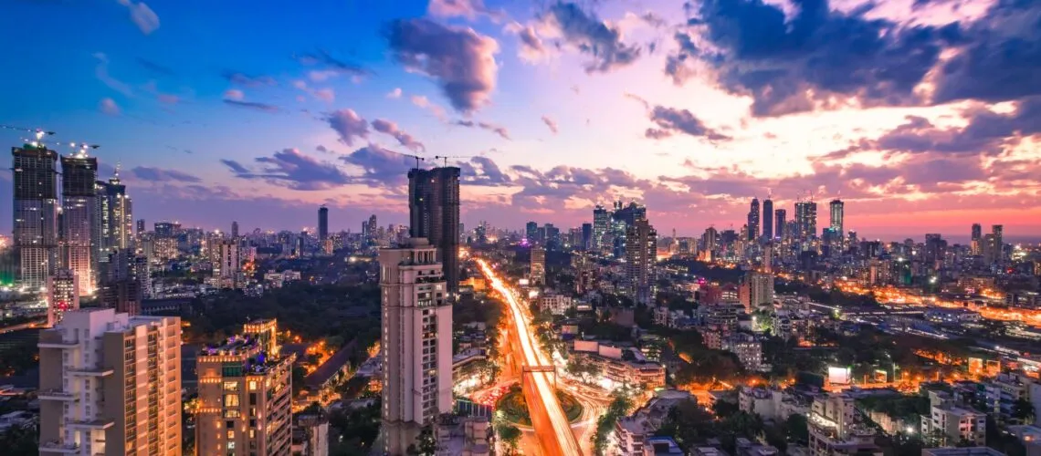 A vibrant cityscape at dusk with illuminated roads and towering skyscrapers under a colorful sky.