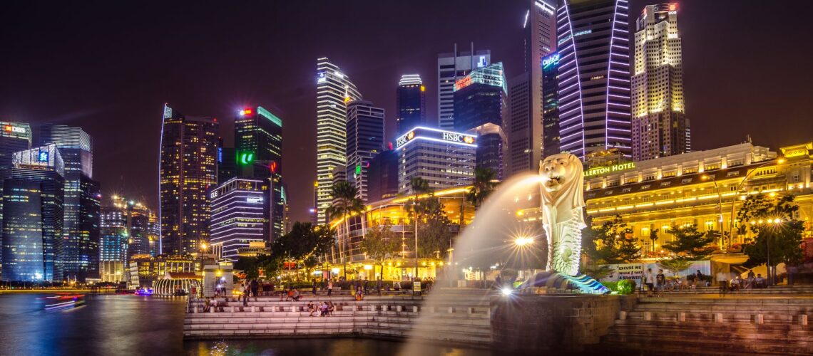 Singapore's skyline at night with the iconic Merlion statue and illuminated skyscrapers.