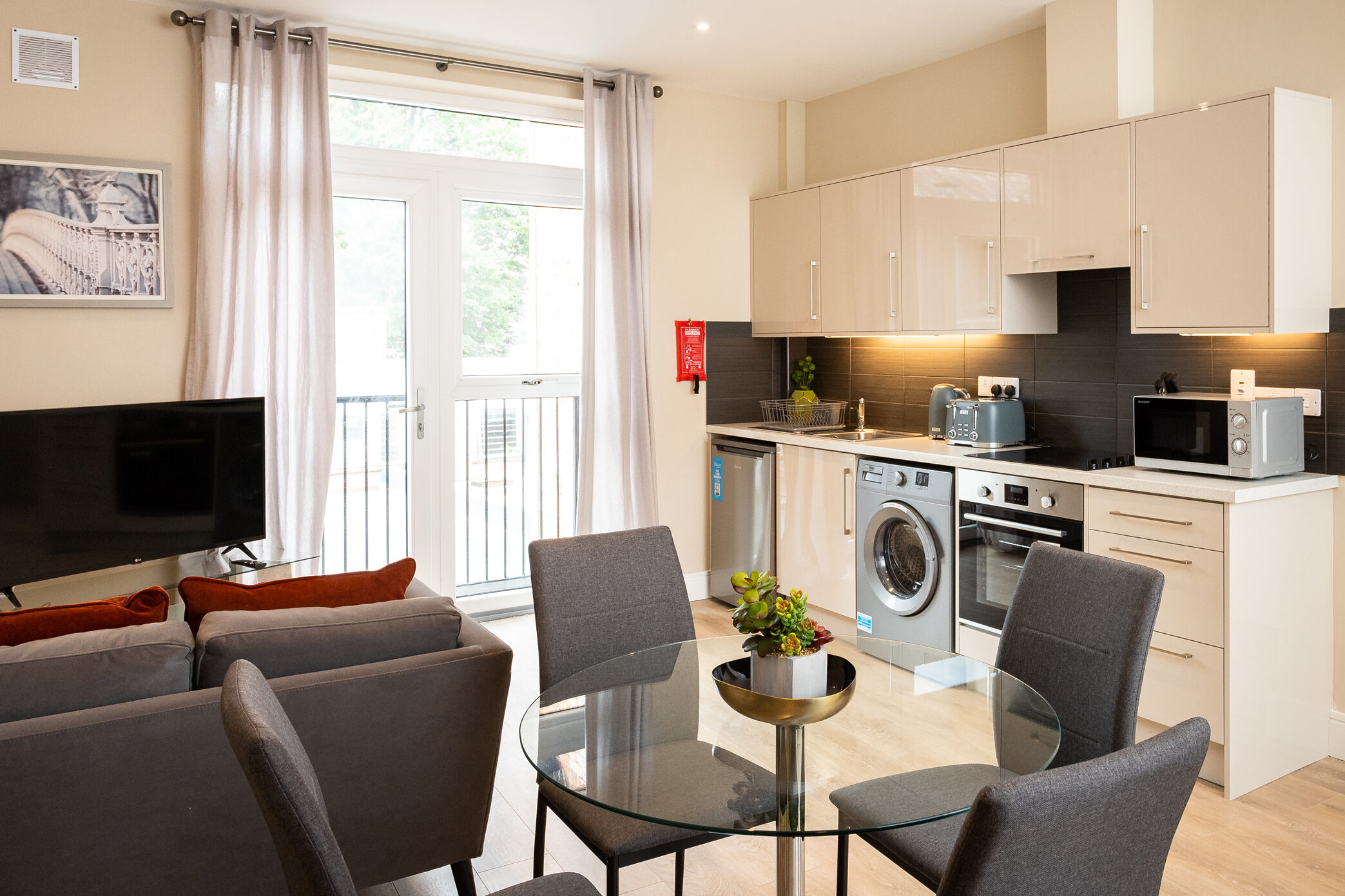 Modern open-plan living space with kitchen, dining area, and balcony access.
