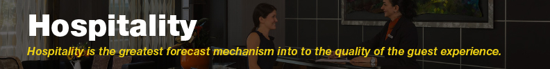 Two individuals interact at a reception desk in a professional hospitality setting.