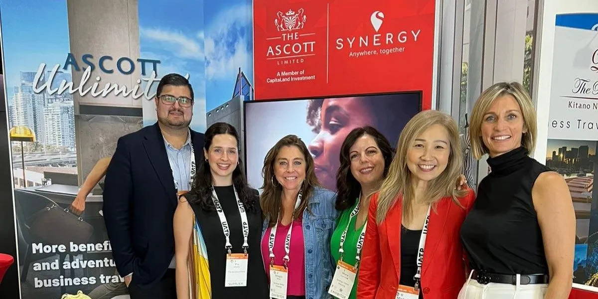 A group of individuals stands at a promotional booth for The Ascott Limited and Synergy Global Housing.