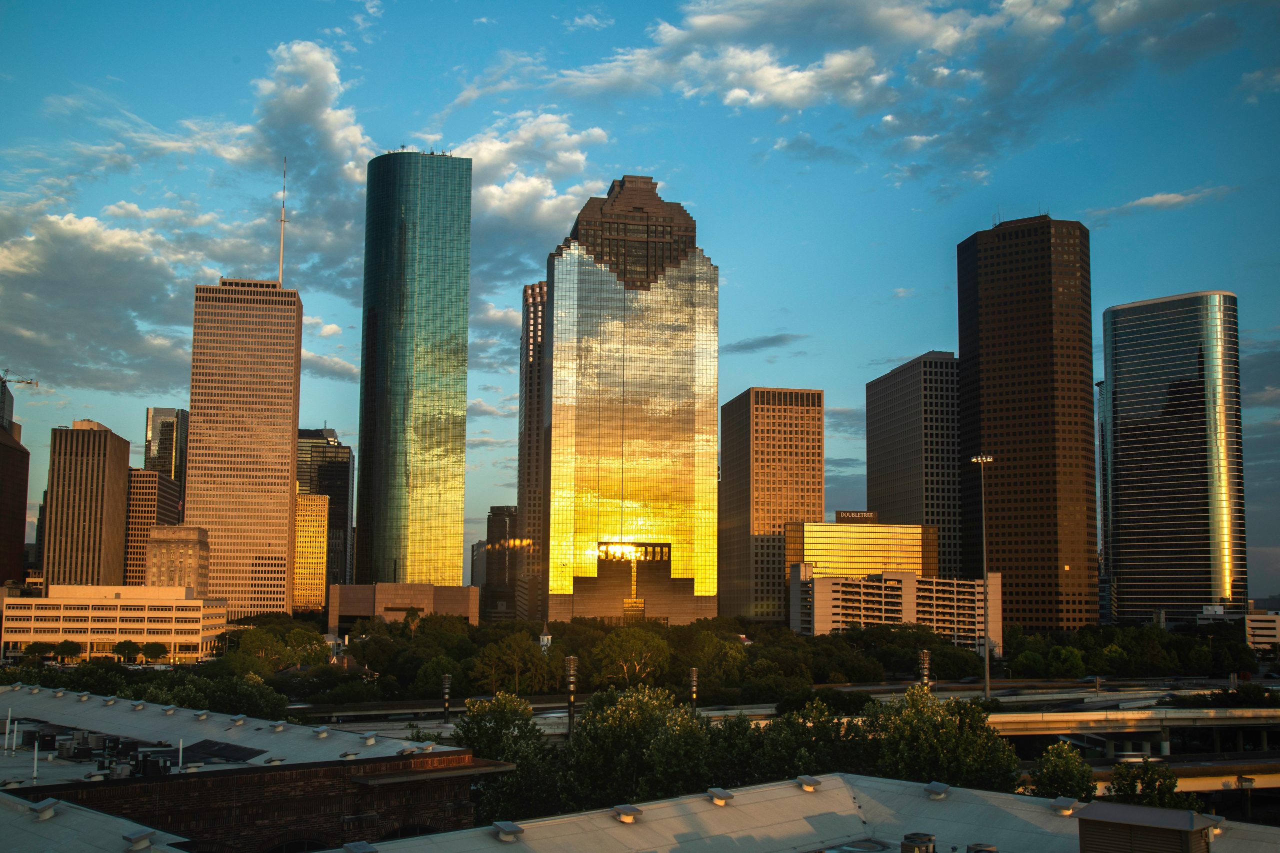 Houston skyline at sunset, with golden reflections on skyscrapers and a vibrant sky backdrop.