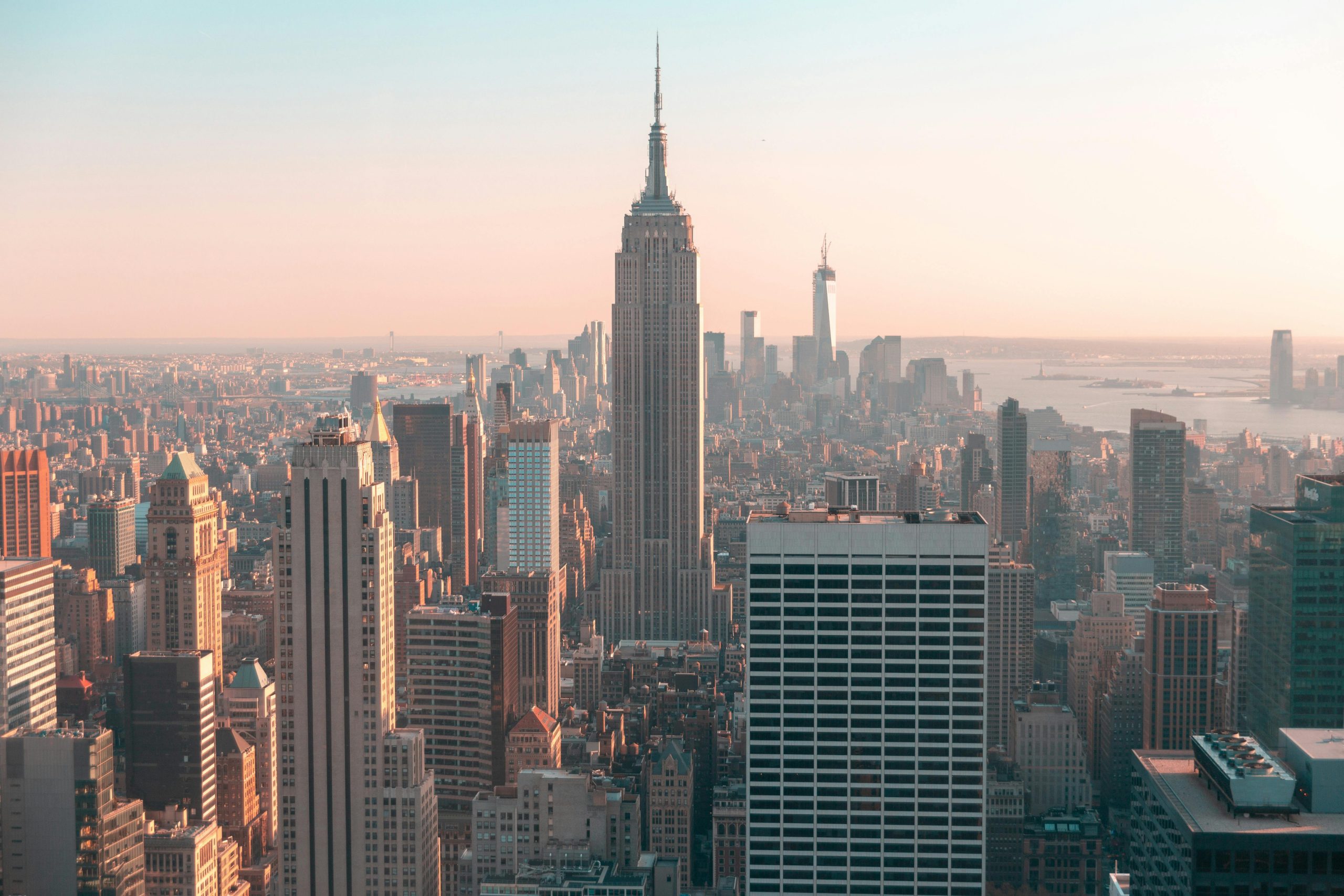 A cityscape featuring the Empire State Building, surrounded by skyscrapers at sunset.
