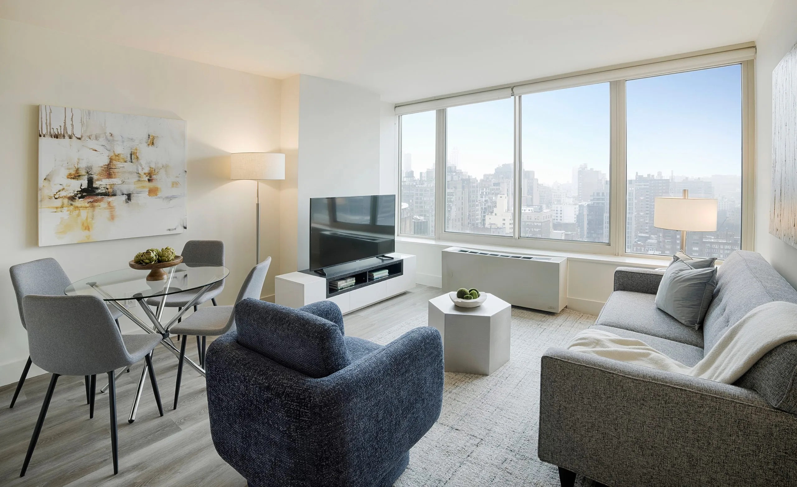 Modern living room with city views, sleek furniture, and neutral-toned decor.