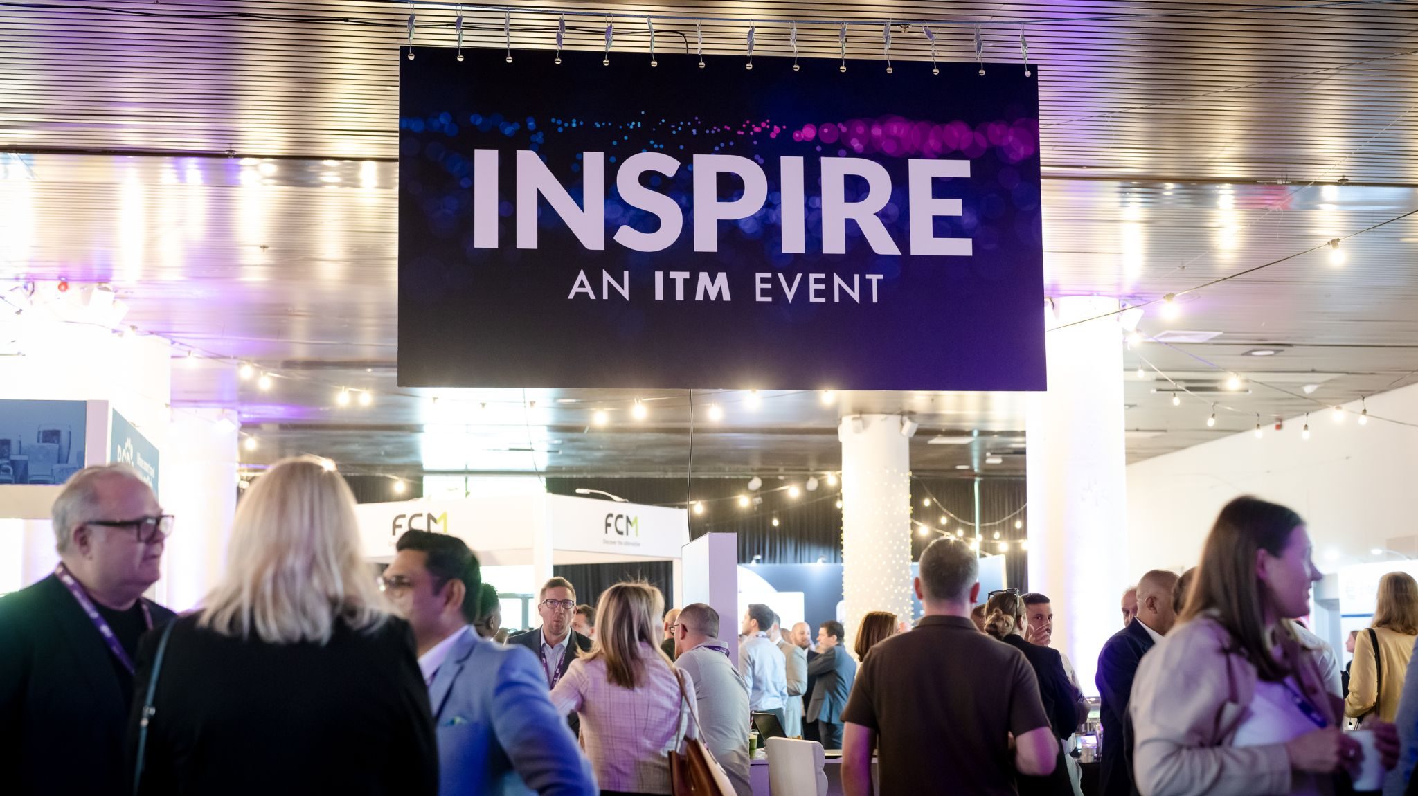 A professional event with attendees networking under a banner reading "INSPIRE: An ITM Event."