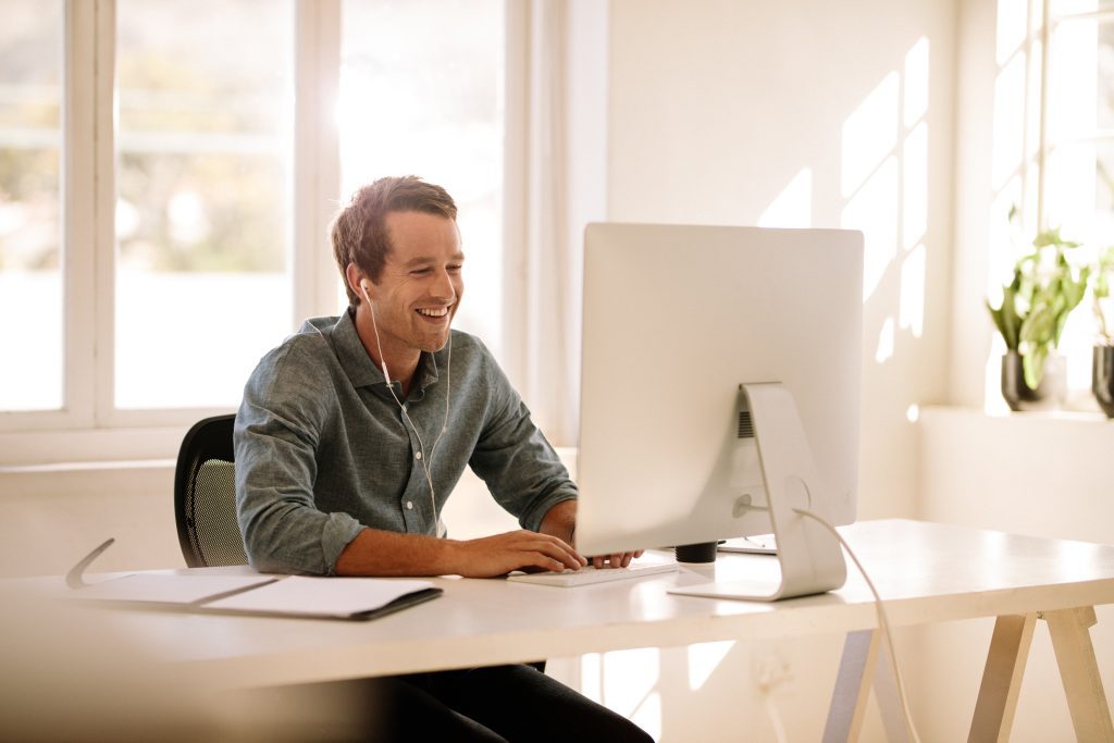 A person works at a desk with a computer in a bright, modern office space with natural light.