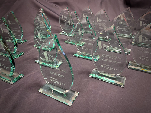 Glass awards with engraved text arranged on a fabric-covered surface.