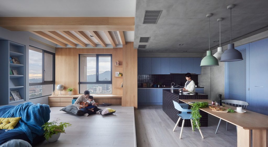 Modern open-plan living space with wood accents, blue tones, and a functional kitchen area.