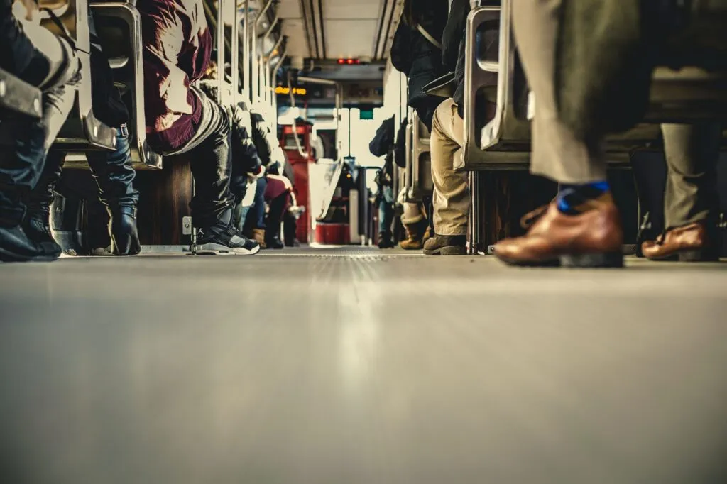 A low-angle view of passengers' legs and shoes inside a public bus, emphasizing urban transit.